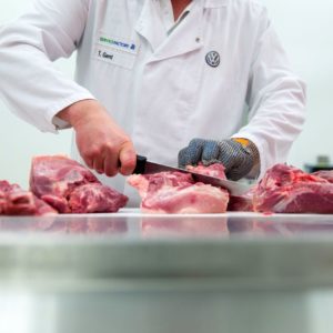 A butcher slices cuts of pork at the currywurst sausage production line in the Volkswagen AG (VW) manufacturing plant in Wolfsburg, Germany. Photographer: Krisztian Bocsi/Bloomberg